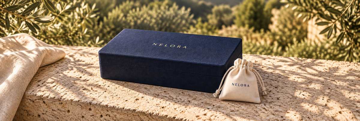 NELORA navy box and drawstring pouch on a sunlit stone table